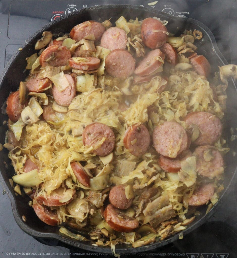 adding sauerkraut and smoked sausages to the pan